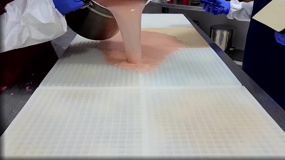 Gummy mixture being poured across a commercial silicone gummy mold during production