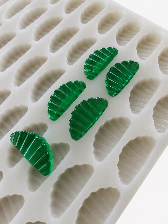 Angled close-up of the 3mL orange slice gummy mold with 140 cavities and emerald green gummy samples
